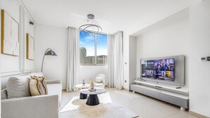 A modern living room with a grey sofa, a coffee table, and a TV on a stand. - New 2BR with Pool & Gym in Green Sobha Community (Dubai)