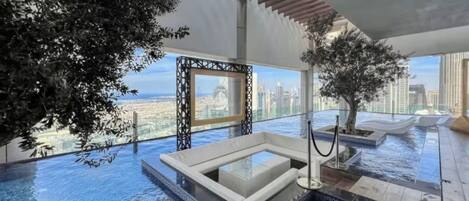 Una piscina infinita interior de lujo con vistas a la ciudad, rodeada de arquitectura moderna y plantas de interior.