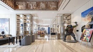 A spacious lobby with a high ceiling, a central seating area, and a statue of a character holding a staff. - Ultra Luxurious! Stunning Views, 64th Floor Pool (Business Bay)