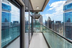 A modern balcony with glass railings, offering a view of surrounding skyscrapers.