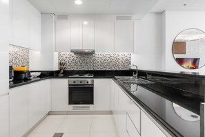 Una cocina moderna con armarios blancos, encimera negra y extractor de acero inoxidable.