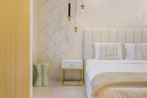 A modern bedroom with a geometric patterned wall, a white bed with a gold frame, and a bedside table with a drawer. - Ultra Luxurious! Stunning Views, 64th Floor Pool (Business Bay)