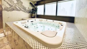 A modern bathroom with a large bathtub, a potted plant, and a city view through large windows. - Ultra Luxurious! Stunning Views, 64th Floor Pool (Business Bay)