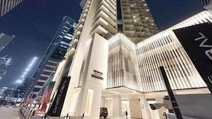 A modern hotel with a prominent corner entrance, large glass windows, and a clean, white facade. - Luxury 2BR  with Stunning Lake View in Business Bay (Dubai)