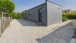 A modern, single-story building with a dark exterior, a gravel driveway, and a wooden fence. - Chalet for 6 - Heated Pool - Terrace (Bretignolles-sur-Mer)