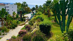 A hotel with a garden pathway, cacti, and palm trees. - Rancho Mirafoles apartment, Sea Views (Mijas)