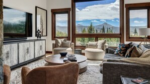 A spacious living room with a large window offering a mountain view, a wooden cabinet, and comfortable seating.