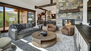 A spacious living area with a fireplace, a sofa, a coffee table, and a view of the mountains.