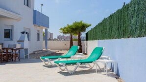 Une terrasse sur le toit avec deux fauteuils de jardin, une petite table et une chaise.