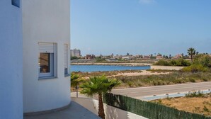 Une vue sur la côte, avec un bâtiment blanc, un palmier et une route menant à une plage.