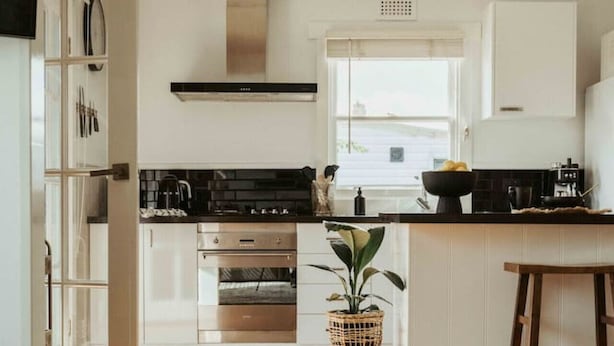 Een moderne keuken met witte kastjes, een zwart aanrecht en een centraal eiland met een plant.