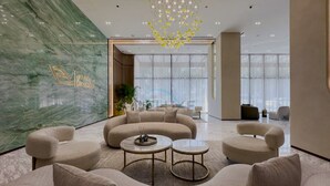 A modern lobby with a curved sofa, round coffee tables, and a chandelier. - Skyline-View 1BR with Balcony,Minutes to Downtown and Marina, Binghatti Onyx, JVC (Dubai)