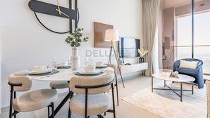 A modern dining area with a round table, chairs, and a clock on the wall. - Skyline-View 1BR with Balcony,Minutes to Downtown and Marina, Binghatti Onyx, JVC (Dubai)
