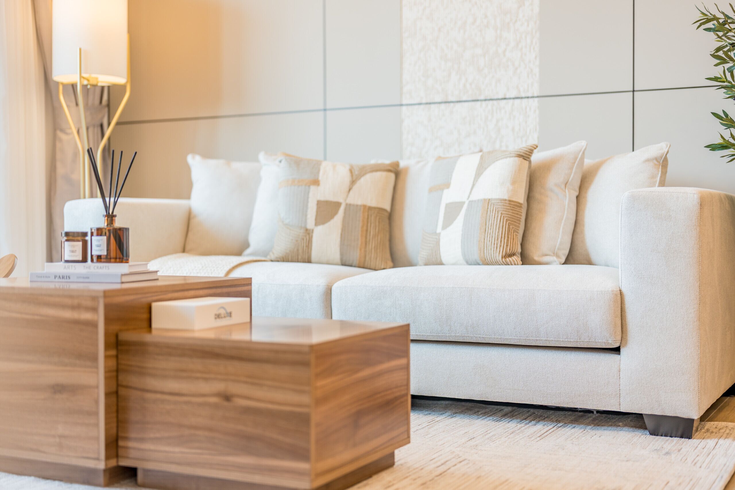 A modern living room with a light-colored sofa, a wooden coffee table, and a patterned rug.