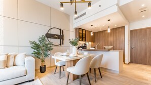 Una cocina moderna con una isla central, armarios de madera y un comedor con una mesa y sillas blancas.