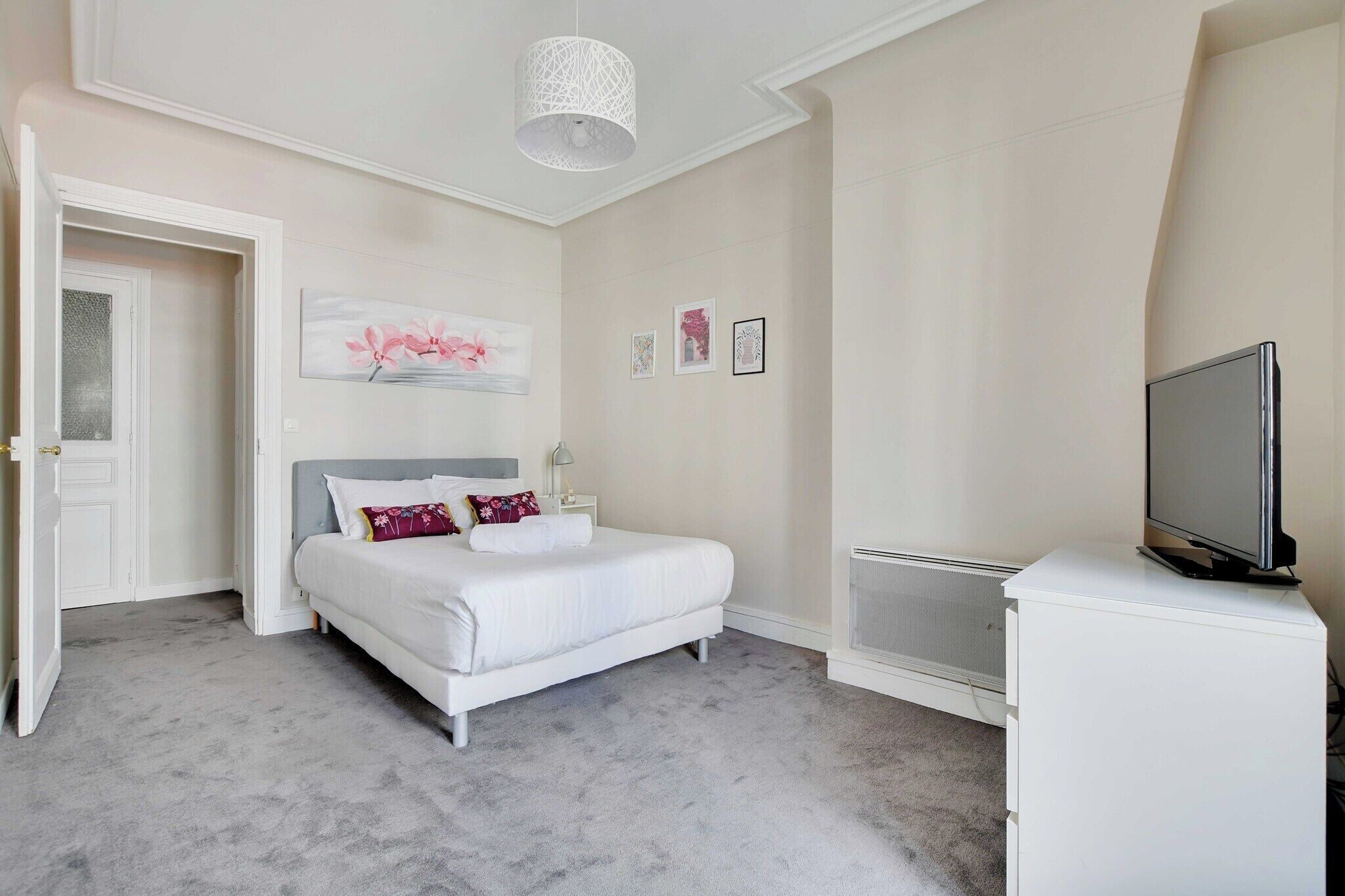 A bedroom with a bed, a TV, and a white dresser.