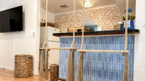 Una cocina con un salpicadero de azulejos azules, una barra de bar de madera y un columpio colgante de cuerda.