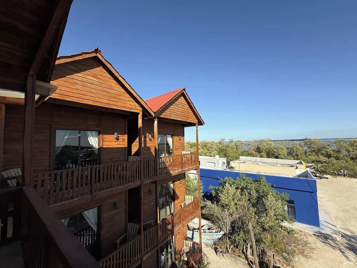 A wooden multi-story building with balconies, a pool, and a clear view of the surrounding landscape.