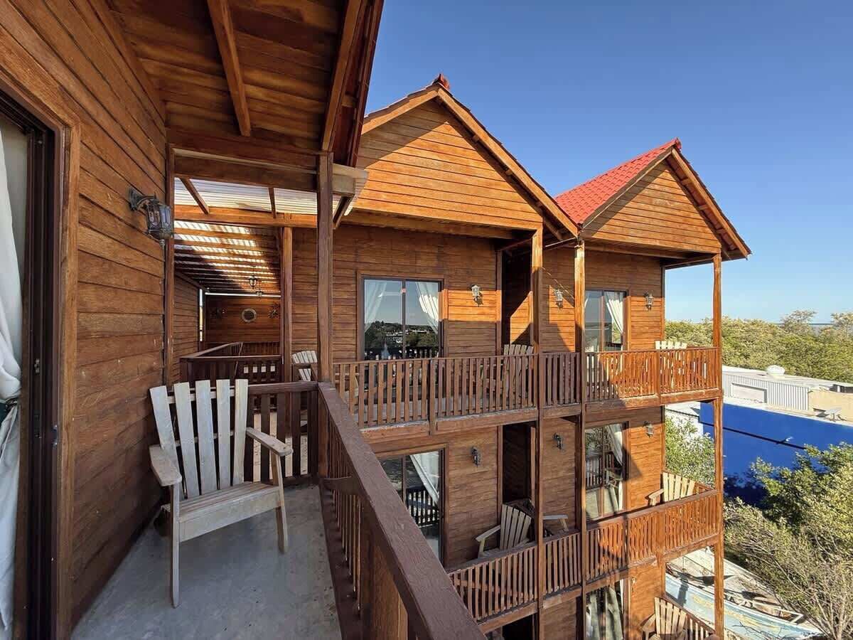 Une cabane en bois dotée d’un balcon, d’une chaise en bois et offrant une vue sur le paysage.