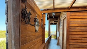 A wooden corridor with a metal railing, a wooden ceiling, and a view of the outdoors.