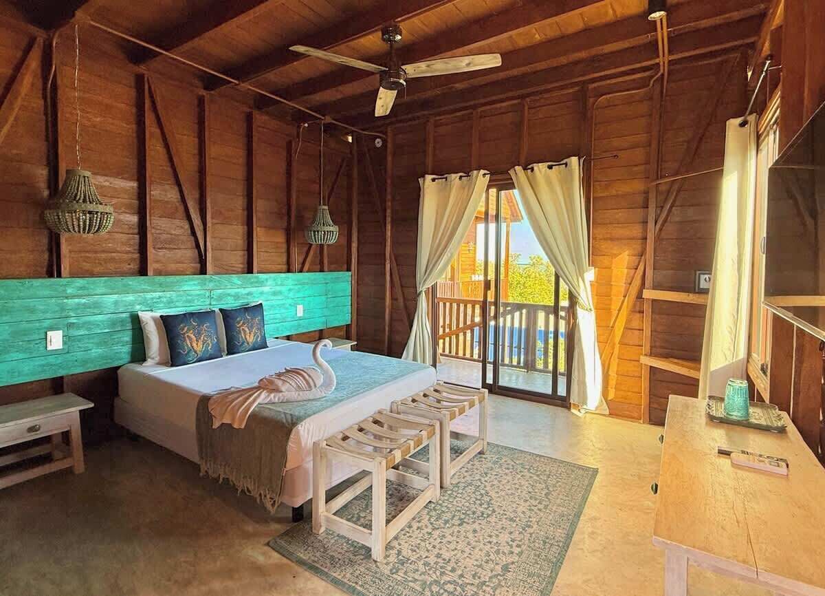 Een slaapkamer in een houten blokhut met een bed, een bankje en een tafel.