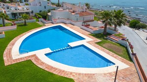 A swimming pool with a curved edge, surrounded by a brick border and a grassy area.