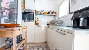 A compact kitchen with white cabinets, a built-in oven, a microwave, and a coffee maker on the counter.