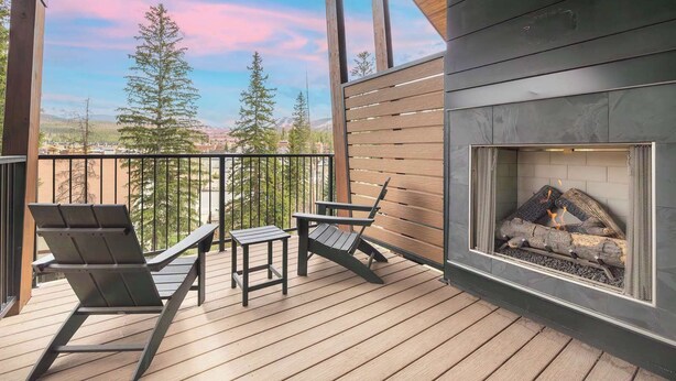 Eine Holzterrasse mit Sitzgelegenheit und Kamin.