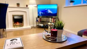 A living room with a coffee table, a television, and a fireplace.