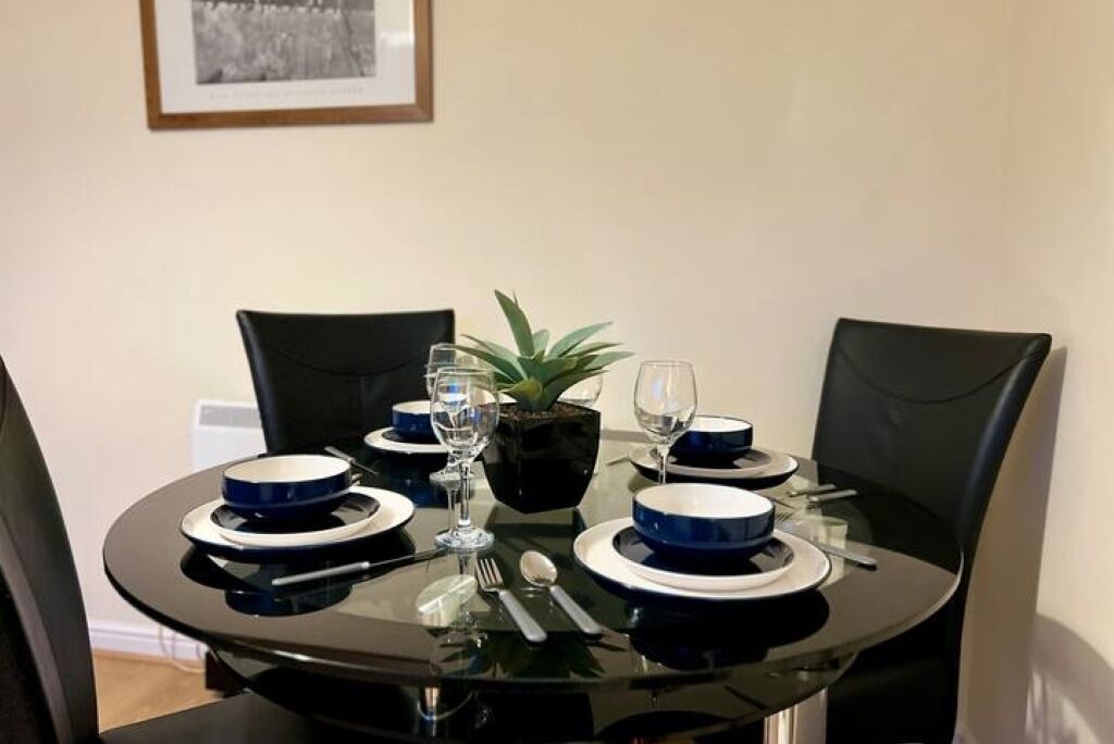 Een eettafel gedekt met blauwe en witte borden, een glas, een lepel en een vork.