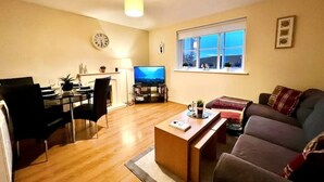 A living room with a dining area, a TV, and a window with a view.