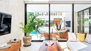 Un salon moderne doté d’une grande fenêtre, d’une piscine et d’un espace salon extérieur.