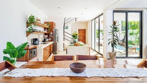 Une cuisine moderne avec un coin repas, des meubles en bois et une vue sur une piscine et un jardin.
