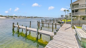 A wooden pier extending into a calm body of water, with a building featuring balconies on the right. - Orange Beach Oasis - Old River Front with 1 minute walk to beach! (Orange Beach)