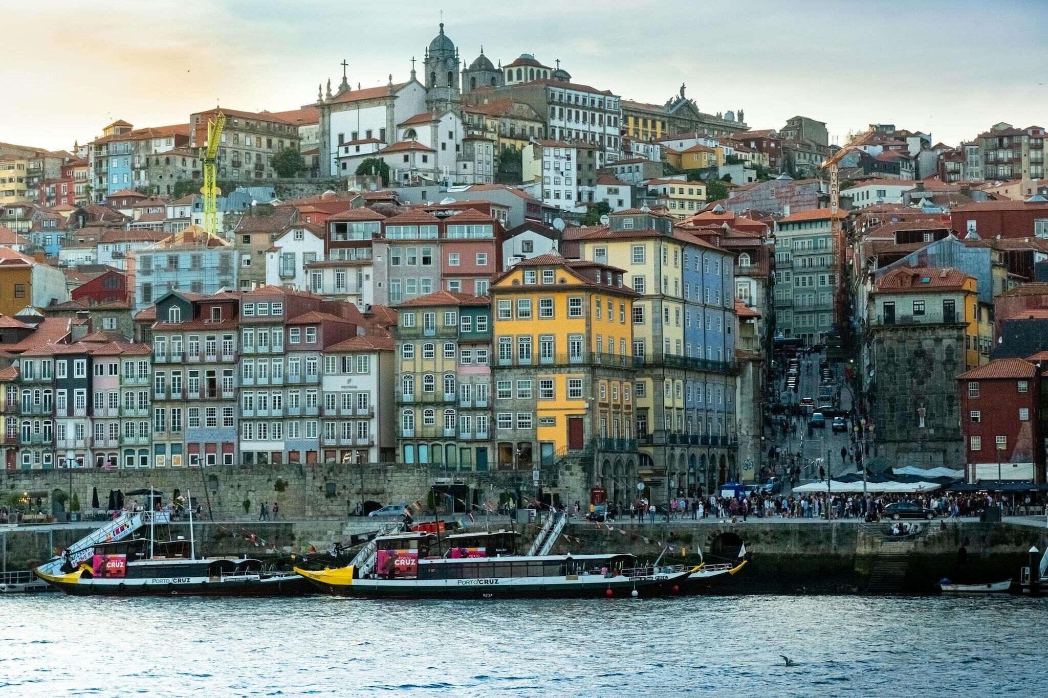 A waterfront cityscape with colorful buildings, a prominent church, and a busy harbor with boats.