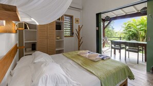 Ein Schlafzimmer mit Himmelbett, Holzregalen und Blick auf eine Terrasse mit Tisch und Stühlen.