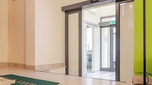 Een hotelingang met een groene deurmat, een glazen deur en een groene muur.