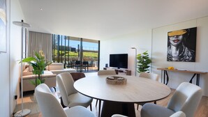 A modern living room with a round dining table, comfortable seating, a flat-screen TV, and a large window offering a view of the outdoors. - Cloud9 by LovelyStay | Heaven with Private Pool (Funchal)