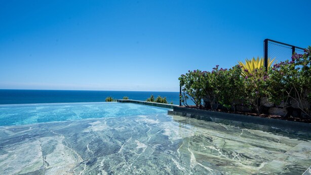 A clear blue sky, a swimming pool with a view of the ocean, and a garden with flowering plants. - Cloud9 by LovelyStay | Heaven with Private Pool (Funchal)