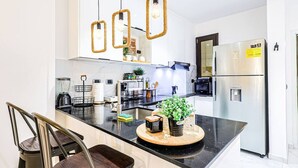 Cocina moderna con una isla central, electrodomésticos de acero inoxidable y una lámpara colgante.