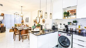 Una cocina moderna con una isla central, electrodomésticos integrados e iluminación colgante.