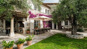A courtyard with a stone table and chairs under a pergola, surrounded by potted plants and a well-maintained lawn. - Bastide Blanche - Five Bedroom Villa, Sleeps 12 (Vence)