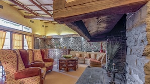 A spacious living room with a stone fireplace, leather sofas, and a high ceiling with exposed beams. - Villa Vasari - Six Bedroom Villa, Sleeps 12 (Reggello)