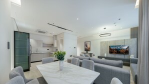 Ein modernes Wohnzimmer mit einem Marmortisch, grauen Sofas und einem an der Wand befestigten Flachbildfernseher.