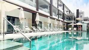 A modern hotel pool with sun loungers and umbrellas, clear blue water, and contemporary architecture. - Coral Cotillo Reef (La Oliva)