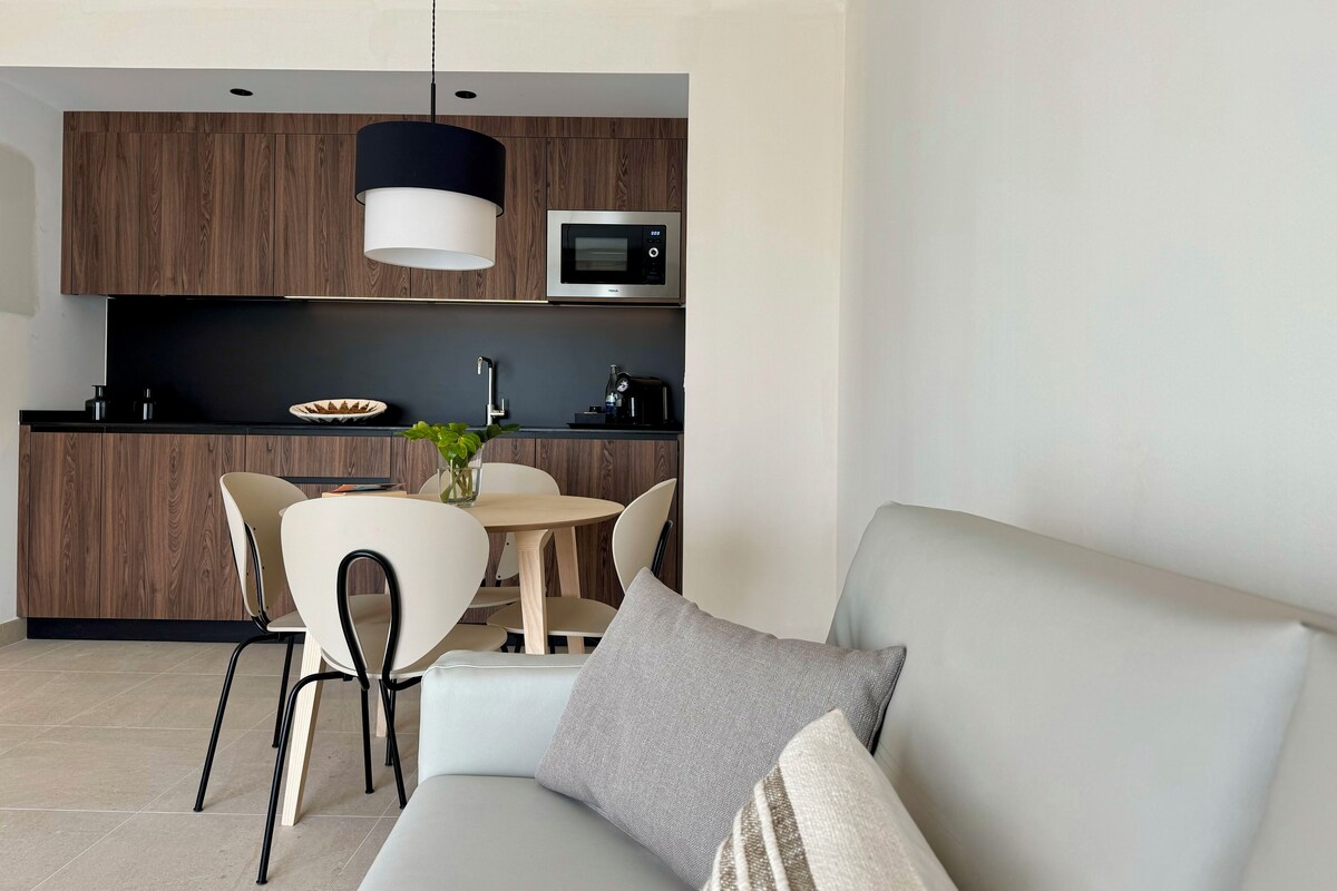 A modern kitchen with dark wood cabinets, a microwave, and a dining area with a round table and chairs.