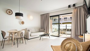 A modern living room with a sofa, dining table, chairs, a coffee table, and a balcony with a view. - Coral Cotillo Reef (La Oliva)