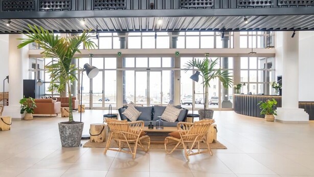 A spacious lobby with a sofa and chairs, large windows, and potted plants. - Coral Cotillo Reef (La Oliva)