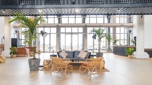A spacious lobby with a sofa and chairs, large windows, and potted plants. - Coral Cotillo Reef (La Oliva)