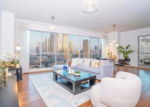 A modern living room with a city view, a sofa, a coffee table, and a dining area with a plant.